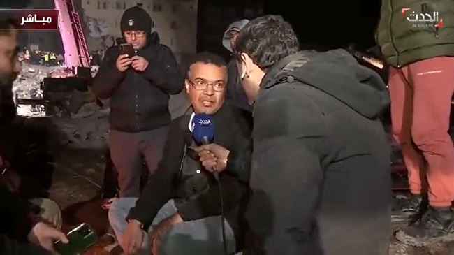 بالفيديو: شاهد يمني على ركام مبنى منهار في تركيا ينتظر نبأ سار بشأن أسرته